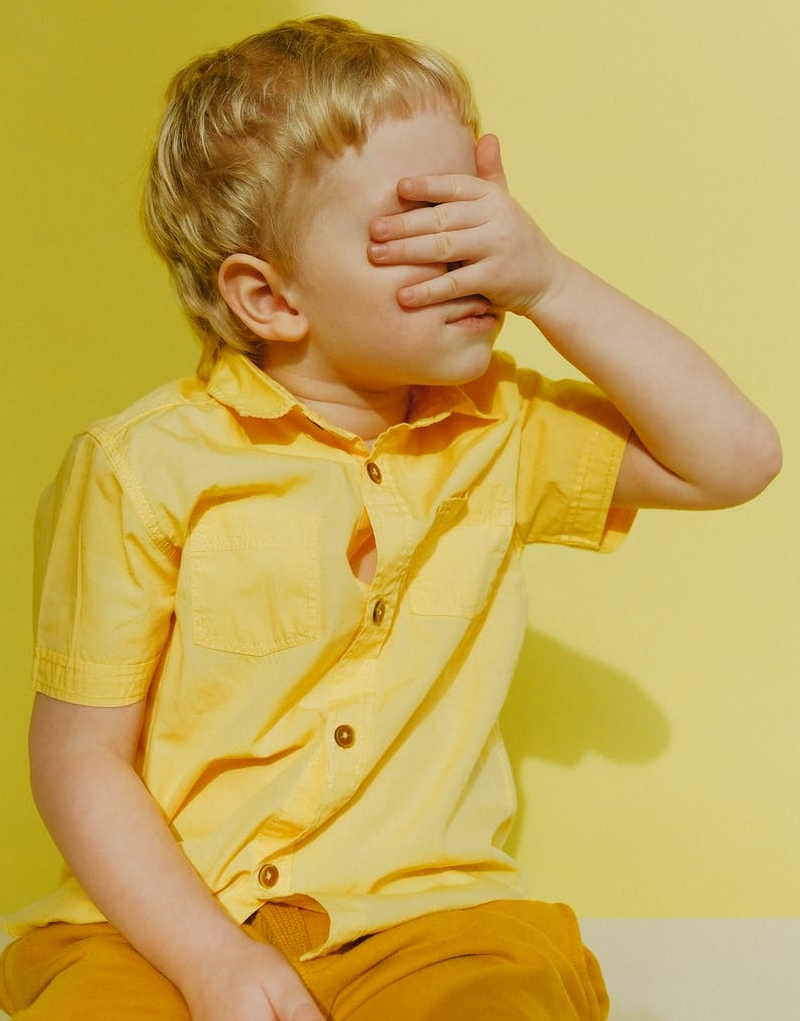 photo of a boy covering his eyes